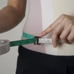 Man using a tape measure to measure his waist